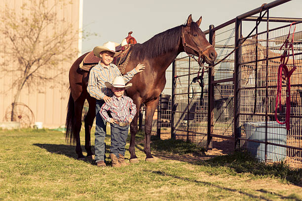 Young Male Ranchers Two young cowboys take a picture with a horse on a ranch in Texas, USA. wild west photos stock pictures, royalty-free photos & images