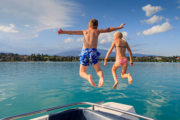 niño y niña de salto en el faakersee en carintia - child jumping swimming nautical vessel fotografías e imágenes de stock