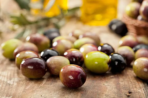 Green and black olives on old table.