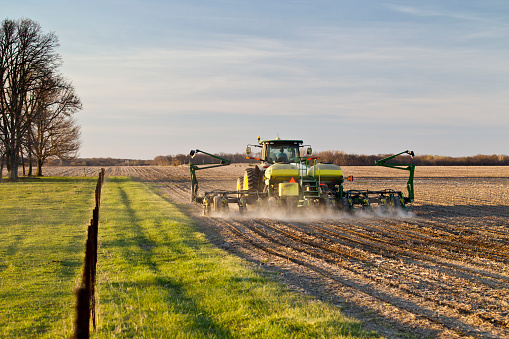 Near Ashland, Illinois, USA - April 14, 2016. Farmer uses modern tractor and corn planter to plant corn in early evening light of central Illinois