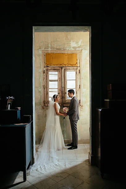 istock Latin newlywed couple holding hands in front window 528279610