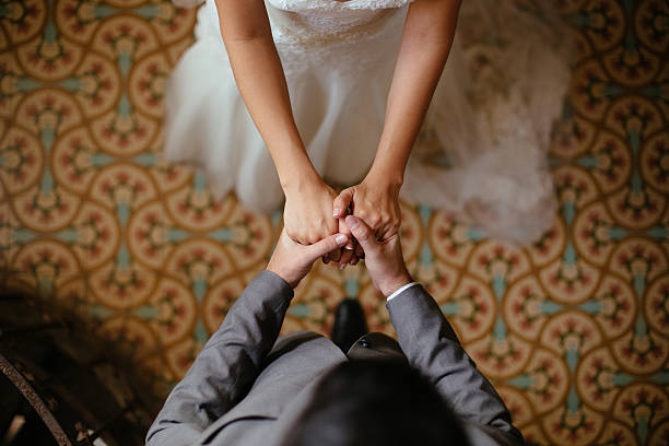Close up shots of bride and groom holding hands A close up shot of a bride and groom holding hands from a top view. newlywed photos stock pictures, royalty-free photos & images