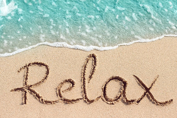 Word Relax handwritten on sandy beach