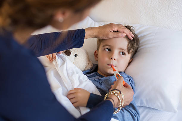 Boy measuring fever Sick boy with thermometer laying in bed and mother hand taking temperature. Mother checking temperature of her sick son who has thermometer in his mouth. Sick child with fever and illness while resting in bed. fever stock pictures, royalty-free photos & images
