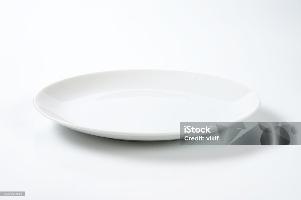 Coup shaped white plate empty rimless white plate on off-white background Plate Stock Photo