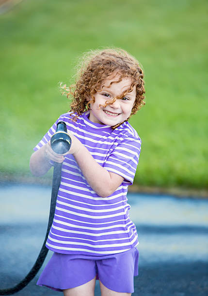 istock Little Girl Spraying Water Hose Towards Camera 528293688
