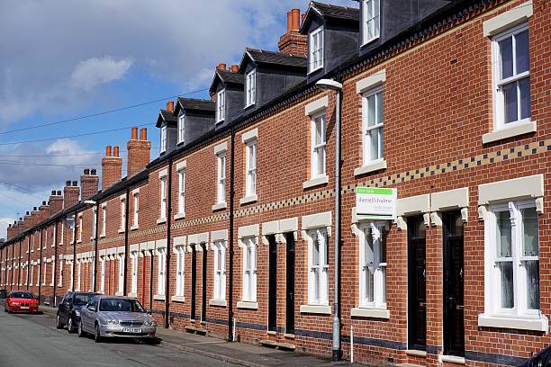 Regenerated Street of Terraced Houses in Stoke-on-Trent, England Stoke-on-Trent, UK - March 29, 2016: A for sale sign hangs in front of a terraced house, part of a street of recently-restored residential properties in Burslem, Stoke-on-Trent. stoke on trent stock pictures, royalty-free photos & images