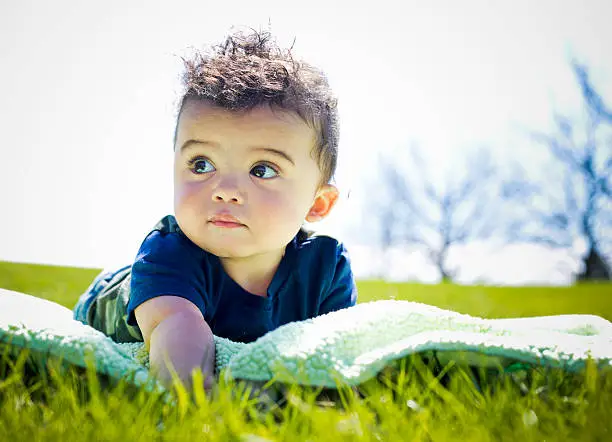 adorable baby boy outdoors posing on green grass