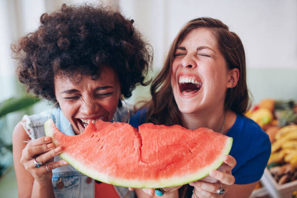 2 つの若い女の子をお楽しみいただける、ウォーターメロン - women eating fruit food ストックフォトと画像