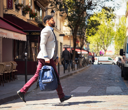 A man stepping out as he quickly crosses a cobbled street in central Paris, France.
