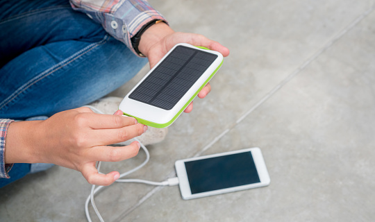 Unrecognizable man charging his cell phone with a portable sun charger device