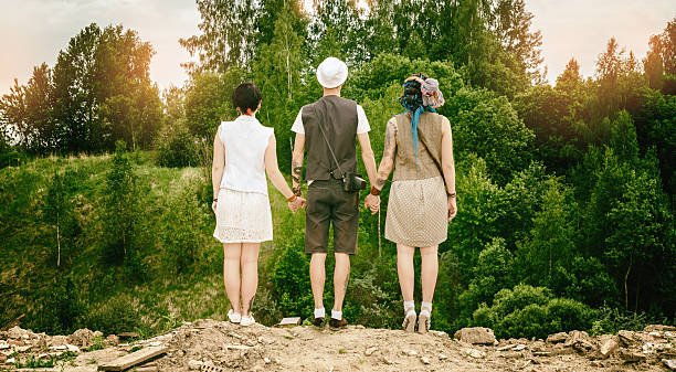young active guy and girls hipsters hold hands over an abyss rear view