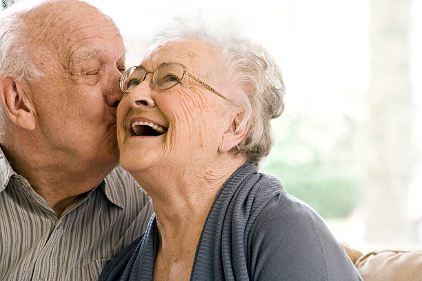 älterer mann und frau auf der couch im altersheim - men senior adult human face smiling stock-fotos und bilder