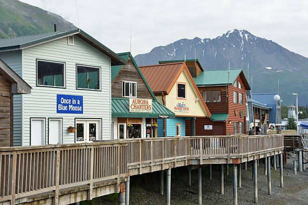 Waterfront Stores at Seward of Alaska Seward, USA - June 27, 2014. Waterfront shops with tourists on deck at Seward. Seward is a scenic port city a the head of Resurrection Bay on the Kenai Peninsula. It is surrounded by Kenai Mountains and the waters of Kenai Fjords National Park and one of the most popular tourist destinations in Alaska. seward alaska stock pictures, royalty-free photos & images