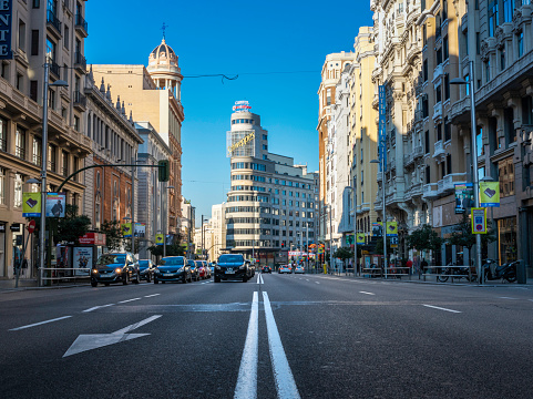 Madrid, Spain - November 10, 2014: Low-angle view of Madrid's busy Gran Vía boulevard on an Autumn early morning, with Callao and the Edificio Carrión building in the background.