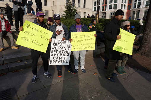 Washington DC, USA-December 13, 2014: These protesters are protesting police brutality at a protest led by Reverend Al Sharpton on Pennsylvania Avenue in Washington DC. They bear signs that include a protest of the strangling death of Eric Garner who died by police hands in Staten Island New York.  Recently the deaths of Michael Brown, Eric Garner and Tamir Rice have upset the black community.