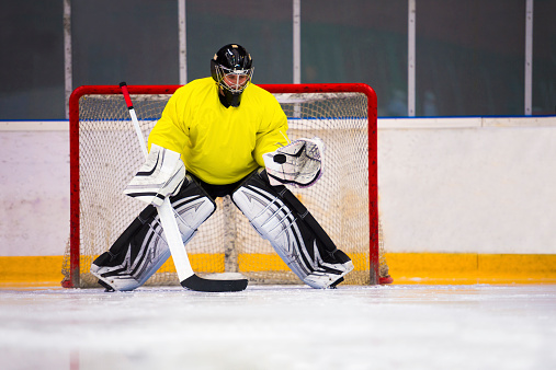 Front view of young ice hockey goalie catching the puck