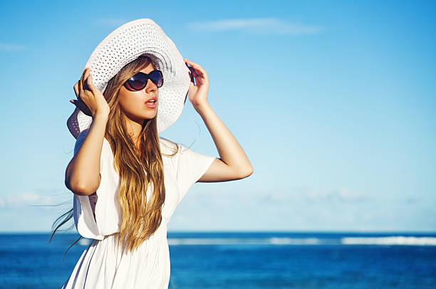 istock Woman in white dress, white hat and sunglasses 528362995