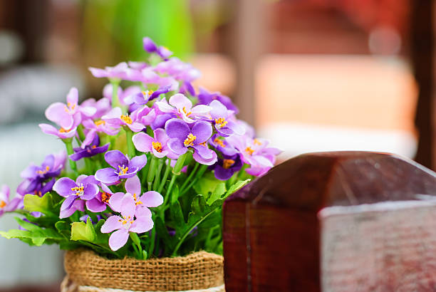 Lively shades of blue and purple Viola tricolor pansies bloom beautifully in large flower beds, enhancing the urban cobbled path with a touch of spring vibrance. People leisurely stroll in this charming cityscape.