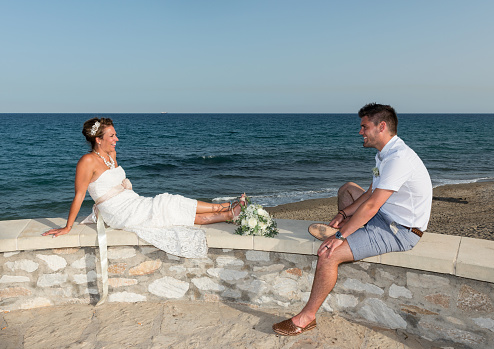 Bride and Groom sitting on a wall next to the Mediterranean Sea Mojacar Spain
