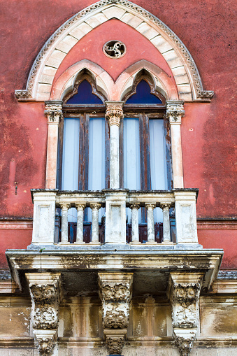 Old (17th-century) Arab/Venetian/Baroque-style window, balcony &  bright pink wall in Siracusa, Sicily, Italy.