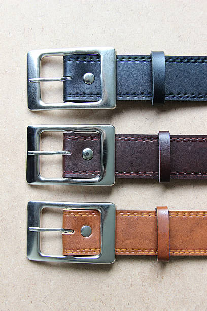 istock Black, dark brown, light brown leather belt on wooden background. 528413245