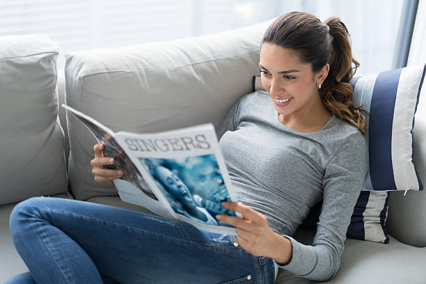 donna rilassante a casa a leggere - newspaper reading holding paper foto e immagini stock