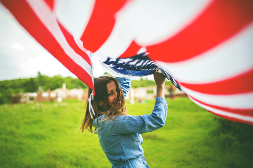 Female Young American girl flying an American flag in the open air