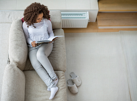 Woman relaxing at home reading on the couch