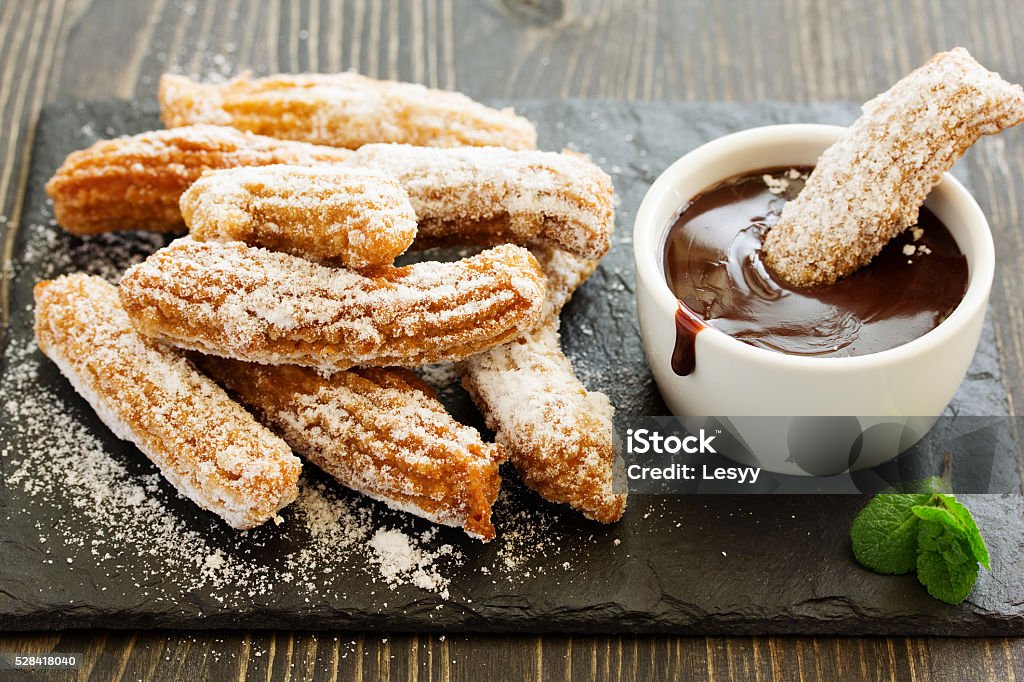 Churros with hot chocolate and powdered sugar. Churro Stock Photo