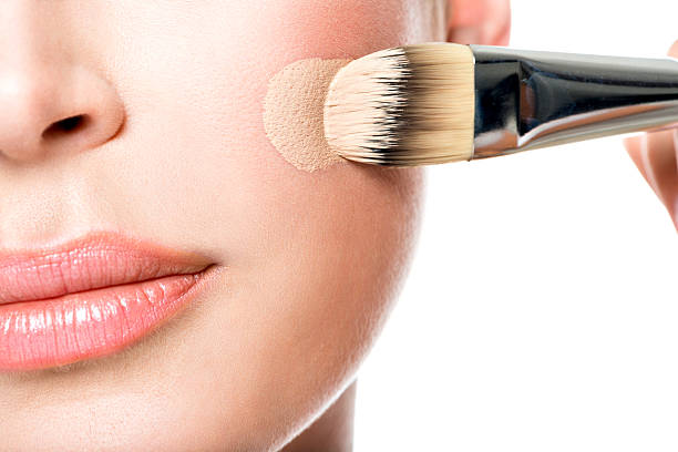 Makeup artist applying liquid tonal foundation on the face Makeup artist applying liquid tonal foundation on the face of the woman. Closeup photo of cheek liquid foundation face stock pictures, royalty-free photos & images