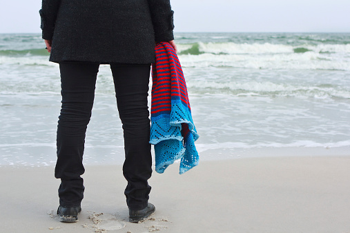 Girl with a knitted shawl on sea beach
