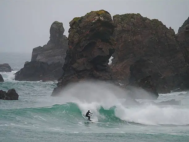 Unkown surfer surfing amongst rock stacks on the Isle of Lewis, West of Scotland.