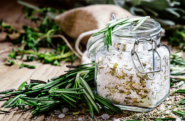 Sea salt with dried rosemary in a glass jar Sea salt with dried rosemary in a glass jar, vintage wooden background, selective focus salt seasoning stock pictures, royalty-free photos & images