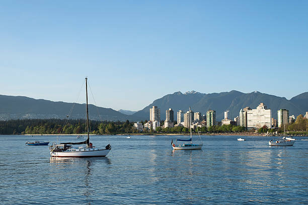 Boats on the ocean in English Bay, Vancouver, British Columbia Tranquil evening time in Kitsilano Dog Beach, Vancouver, British Columbia, Canada. Sailing boats are resting on the ocean while looking at the city skyline in English Bay. People are having leisure time and enjoying the sunset in English Bay. beach english bay vancouver skyline stock pictures, royalty-free photos & images