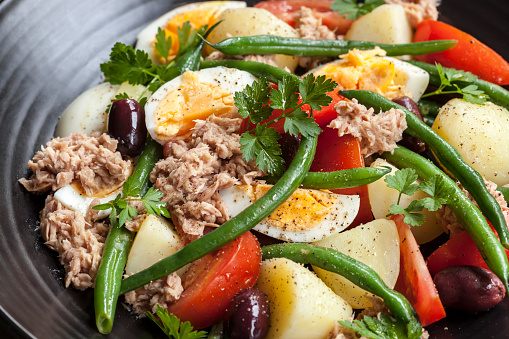 Salad nicoise.  Tuna with baby potatoes, eggs, beans, tomatoes, olives and parsley.