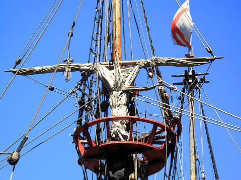 A majestic sailing ship mast rises tall and proud against the endless expanse of a clear blue sky, a symbol of timeless adventure and exploration.