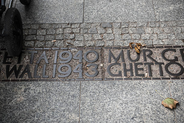 Warsaw, Poland - September 11, 2015: The wheel of a baby stroller crosses over what was once the border of the Warsaw Ghetto in Warsaw, Poland. The Warsaw Ghetto was the largest of all Jewish ghettos in Nazi-occupied Europe during World War II, with approximately 450,000 Jews living in it. Nearly 100,000 died of hunger, and nearly 300,000 were killed in the gas chambers of Treblinka. 13,000 died in what would be known as the Warsaw Ghetto Uprising.