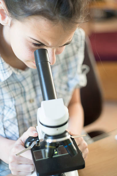 istock Teenage girl make homework scientific project with microscope 528433118