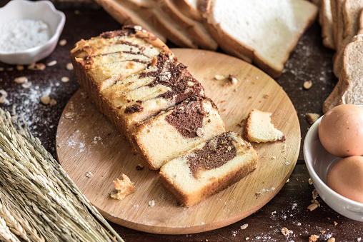 Chocolate marble cake on cutting board with bread and ingredient in kitchen