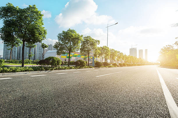 vacía carretera asfaltada en la moderna de la ciudad al atardecer - urban road fotografías e imágenes de stock