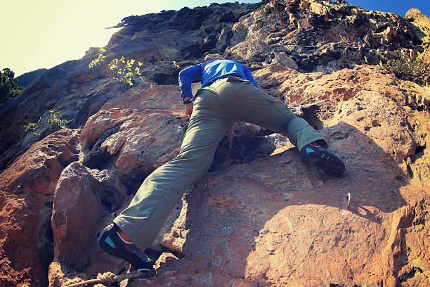 Man rock climbing on steep cliff wall during outdoor adventure sport and extreme activity, person in nature background