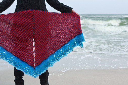 Girl on sea beach shows knitted shawl