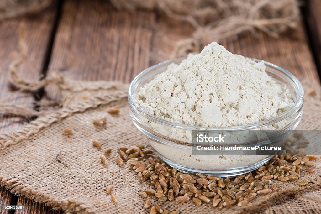 Bowl with Spelt Flour Small bowl with Spelt Flour and whole seeds on wooden background Flour Stock Photo