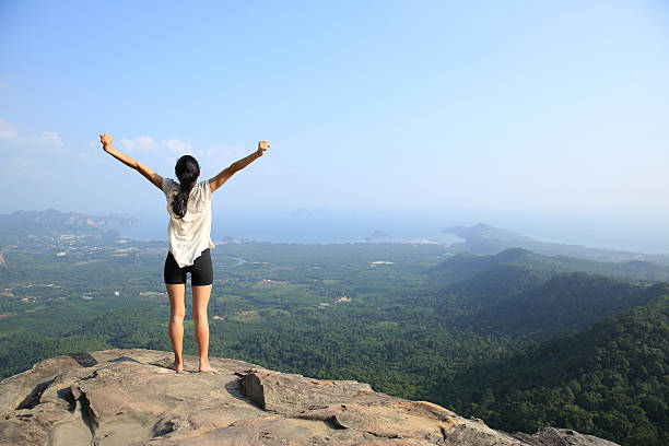 istock young woman open arms  at mountain peak cliff 528438442