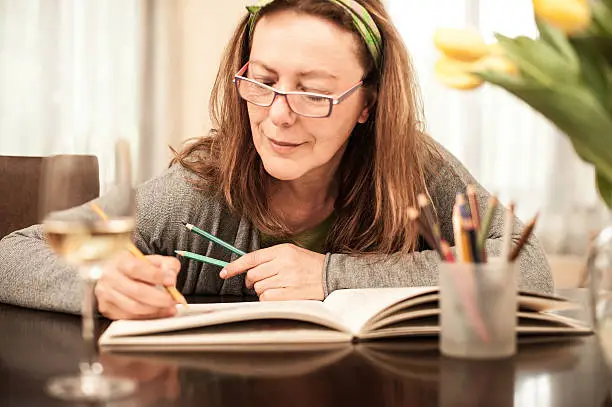 Photo of Mature woman coloring and drinking white wine