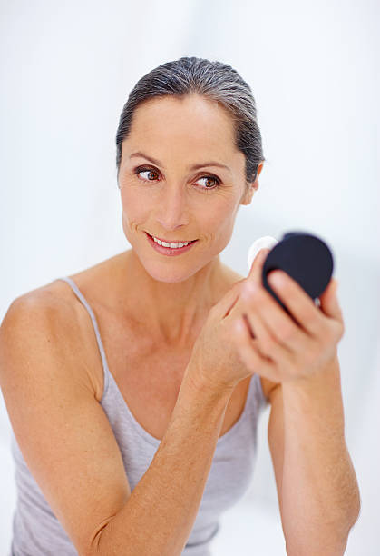 Woman with eyeshadow palette and brush at dressing table, closeup
