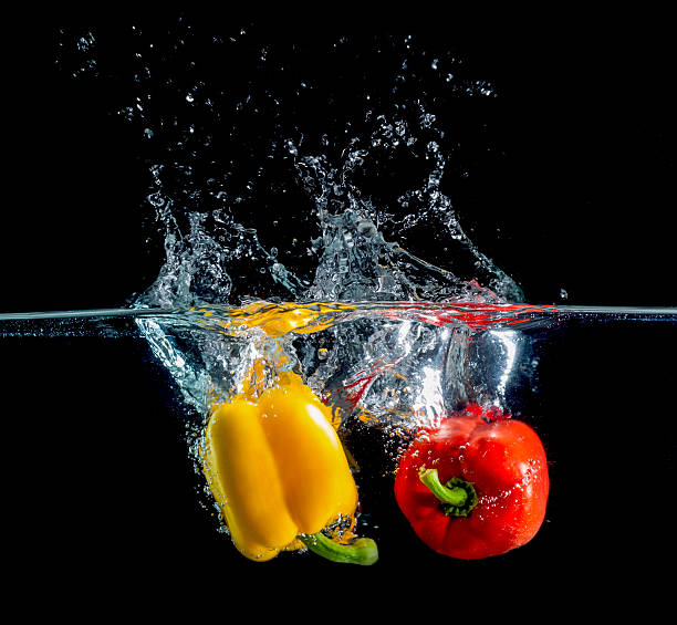 istock yellow and red pepper falling and splashing into water. 528440759