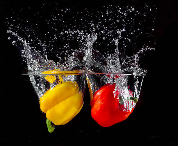 istock yellow and red pepper falling and splashing into water. 528440767