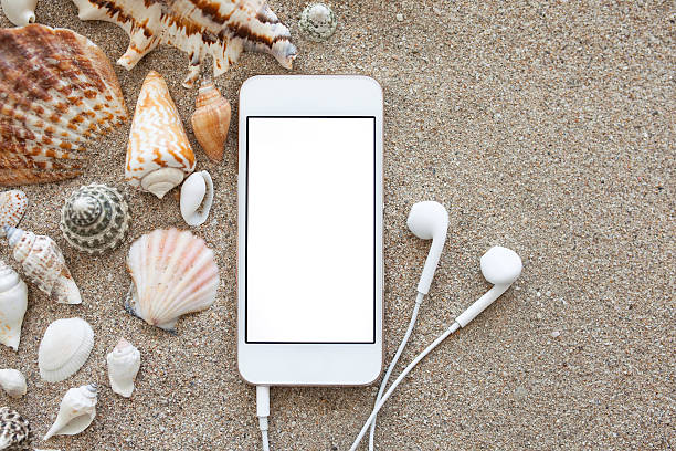 téléphone avec écran isolé et des écouteurs sur le sable - tourist resort audio photos et images de collection